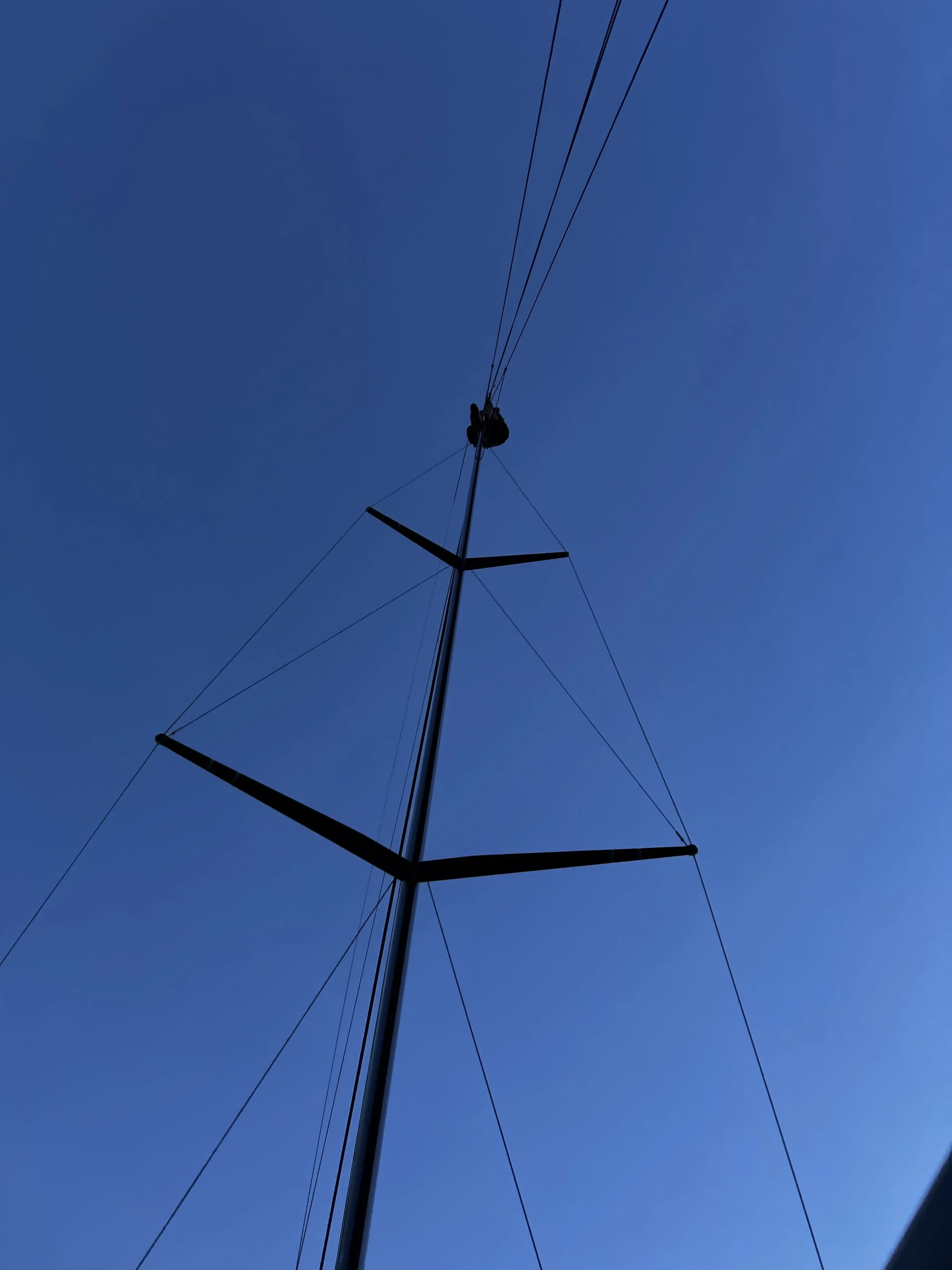 A rigger climbing a mast to service hardware aloft.